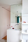 Contemporary bathroom with white panelled washstand in niche and fitted cupboards in background