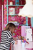 Junges Mädchen am Schreibtisch in nostalgisch gestaltetem Kinderzimmer