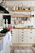 White country-house kitchen with floating wooden shelves of crockery