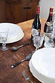 White pace settings and wine bottles on rustic wooden table