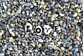 Letters on pebbles spelling out 'Love' on gravel surface