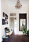 Elegant hallway with gallery of pictures, antique couch and cloakroom mirror; view along hallway with interior doors in background