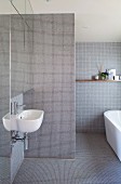 Minimalistisches Bad mit hellgrauen Mosaikfliesen, seitlich in Nische Waschbecken unter Spiegelschrank