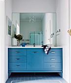 Fitted washstand with blue base cabinets below mirrored wall in rustic bathroom