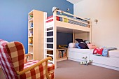 Loft bed with integrated shelving and single bed in modern, child's bedroom with one blue wall