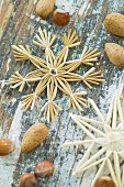 Christmas arrangement of straw star, hazelnuts and almonds on table