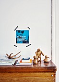 Alter Turnkasten als Ablage für Zeitschriften und Dekofiguren, dahinter mit Masking Tape ein Foto mit Sinnspruch an die Wand gepinnt
