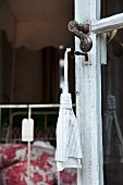 A fabric tag hanging on a key in an old patio door of a French country house with a price label on a metal bedstead in the background