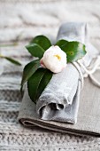 White gardenia decorating rolled linen napkin