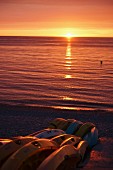 Romantischer Sonnenuntergang über dem Meer, Boote am Ufer
