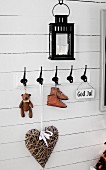 Collection of vintage nick-nacks hanging from coat pegs on white wooden wall