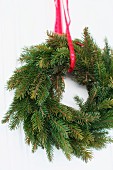 Wreath of fir branches hanging from red ribbon