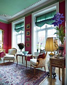 Rococo-style lounge chairs and side table in front of lattice windows with Roman blinds and deep pink walls in grand interior