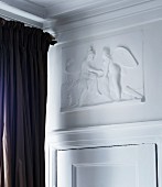 Weißes mytisches Halbrelief über traditioneller Zimmertür, seitlich dunkelbrauner Vorhang