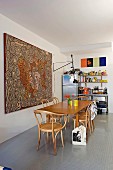 Grossformatiges Aborigines-Kunstwerk hinter Esstisch mit Bugholzstühlen, bunt bestücktes Küchenregal im Hintergrund