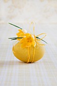 Boiled hen's egg dyed yellow and decorated with crocuses and yellow cord