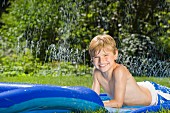 Junge liegt auf einer Wasserrutsche im Garten