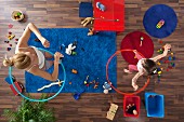 A mother and daughter using hula hoops in their living room, overhead view