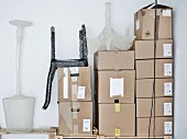 Mesh sculptures of designer lamps and chair on stacked shipping cartons in corner