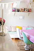 Chairs at table in front of white bench with scatter cushions in feminine dining room