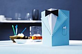 Elegante Einladungskarte aus hellblauem Fotokarton gefaltet für einen Herrenabend
