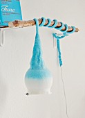Hellblaue, dänische Wandleuchte mit Filzmütze um ein Stück Ast gewickelt