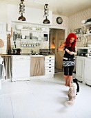 Woman with cats in white, rustic, country-house kitchen
