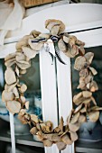 Hand-crafted wreath of leaves hung on door of glass-fronted cabinet