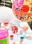 Floral print on lantern above table set in bright colours for garden party