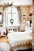 Bed with white lace bedspread in traditional bedroom in shades of white and beige