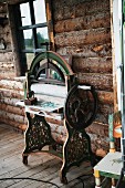 Vintage sewing machine against outside wall of log cabin