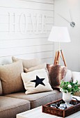 Sofa with scatter cushions below letters spelling 'Home' on white wooden wall