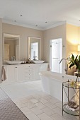 Elegant bathroom with free-standing bathtub on tiled floor and washstand with twin countertop basins
