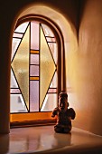 Folklore-Kunst vor kleinem Buntglasfenster mit Rundbogen in Santa Fe (New Mexico)