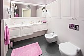 Lilac towels giving a touch of colour to an elegant bathroom with white, built-in cupboards and a grey floor