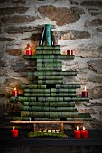 Stylised Christmas tree made from stacked, green antiquarian books with red candles