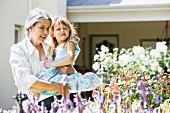 Grossmutter mit Enkelin auf dem Arm beim Betrachten der Blumen im Garten