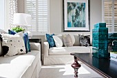 Zeitgenössisches Wohnzimmer mit weissen Sofas, Couchtisch aus Holz & Lamellenfenstern