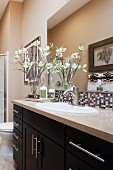 Bathroom sink with mirror and decorative flowers; Rancho Mission Viejo; California; USA