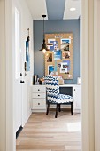 Blick auf Zimmerecke mit Schreibtisch, Polsterstuhl, Hängeleuchte & selbstgestaltetem Wandbild als Dekoration