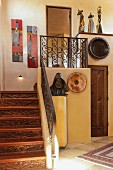 Flurbereich mit Holztreppe, schmiedeeisernem Treppengeländer & antiken Kunstobjekten als Deko (Santa Fe New Mexico)