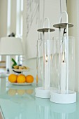 Cylindrical glass candle lanterns on glass surface