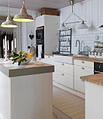 Bowl of fruit and candles on counter below retro pendant lamp in white, country-house-style kitchen