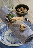 Place setting with blue and white crockery, quail eggs on napkin and name card