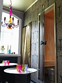Oriental ambiance with colourful glasses and patterned wallpaper; open door leading into sauna