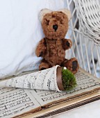 Schultütenförmig, gewickeltes Notenpapier mit Moos auf Notenbuch und Teddybär