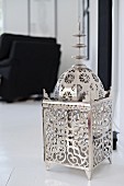 Silver, Oriental-style lantern on white floor