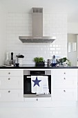 Black and white kitchen counter with stainless steel extractor hood and subway tiles on wall