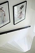 Framed, artistic photos above black handrail of winding staircase