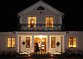 Beleuchtete Villa in der Nacht mit Kerzenlicht auf Veranda